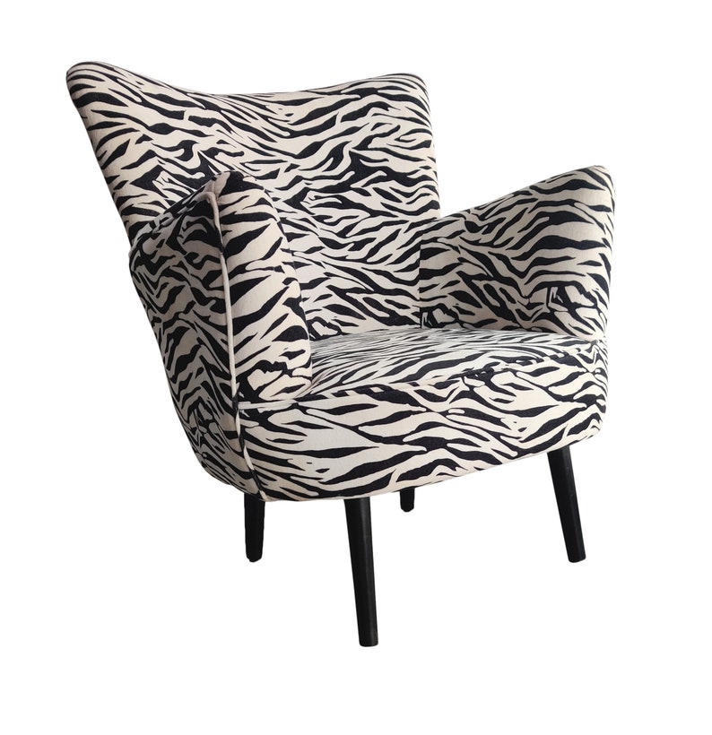 May include: A black and white zebra print armchair with black wooden legs.
