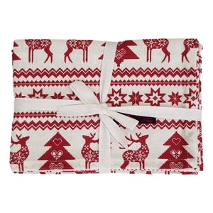 May include: A set of folded Christmas-themed fabric napkins tied with a white ribbon. The napkins feature a repeating pattern of red reindeer, trees, and geometric designs on a cream background. The overall theme is festive.