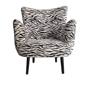 May include: A black and white zebra print armchair with black wooden legs.