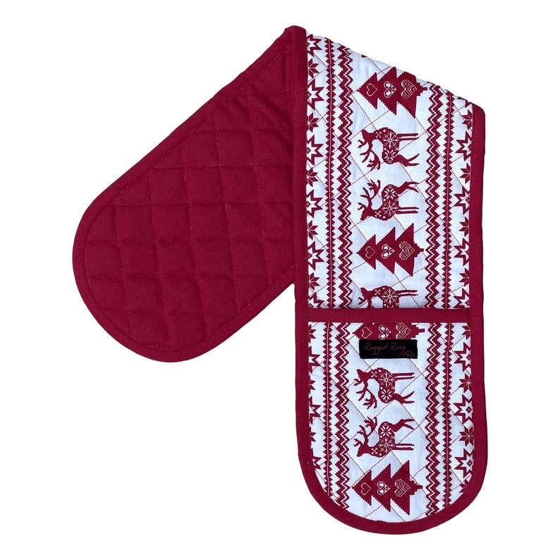 May include: A quilted, double oven mitt in a festive Christmas theme. The mitt is primarily burgundy with a white patterned section featuring reindeer and Christmas trees. The brand name "Ragged Rose" is printed on a small label.