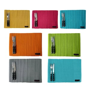 May include: Set of six placemats in various colors, including yellow, pink, orange, green, gray, and blue. Each placemat features a woven texture and is paired with a fork and knife.