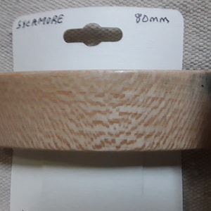 May include: A light brown wood veneer sample with a grainy texture. The sample is labeled "SYCAMORE" and "80mm".