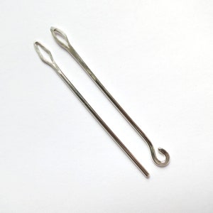 May include: Two silver crochet hooks, one with a loop at the end.