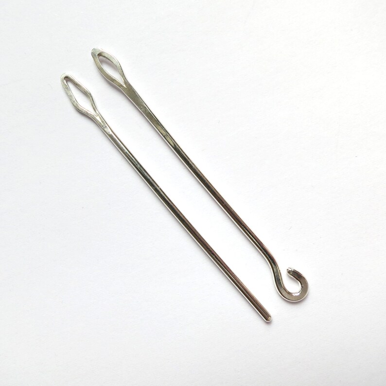 May include: Two silver crochet hooks, one with a loop at the end.