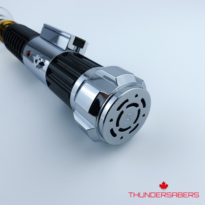 May include: A chrome and black lightsaber with a silver hilt and a black grip. The lightsaber has a detailed design with a circular end cap. The image includes the text "THUNDERSABERS".