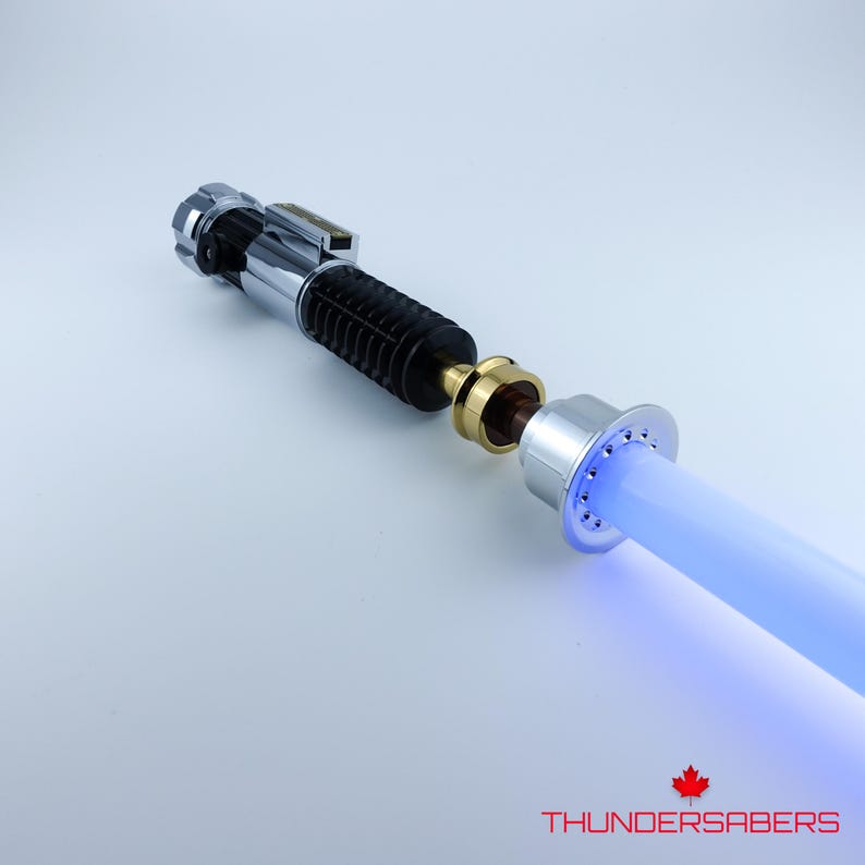 May include: A disassembled lightsaber with a blue blade. The hilt is silver and black with gold accents. The blade is a bright, glowing blue. The text "THUNDERSABERS" is visible in red.