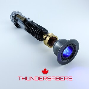May include: A detailed lightsaber prop with a silver, black, and gold handle. The emitter glows with a bright blue light. The text "THUNDERSABERS" is displayed in red below the prop, along with a red maple leaf.