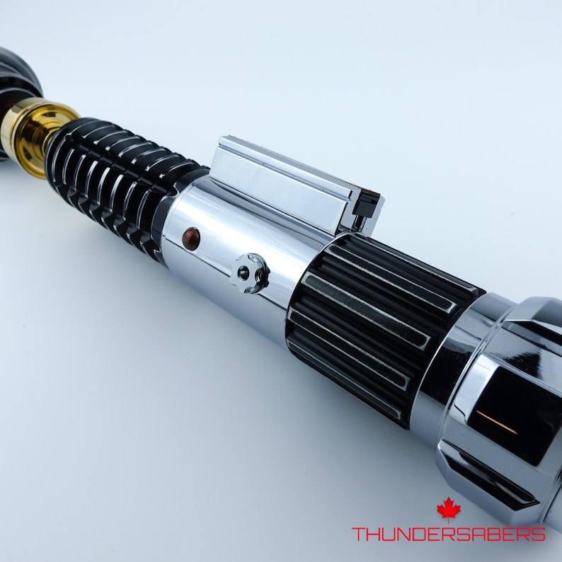 May include: A detailed lightsaber with a silver and black handle, and gold accents. The design includes a series of ridges and a polished finish. The text "THUNDERSABERS" is visible at the bottom.