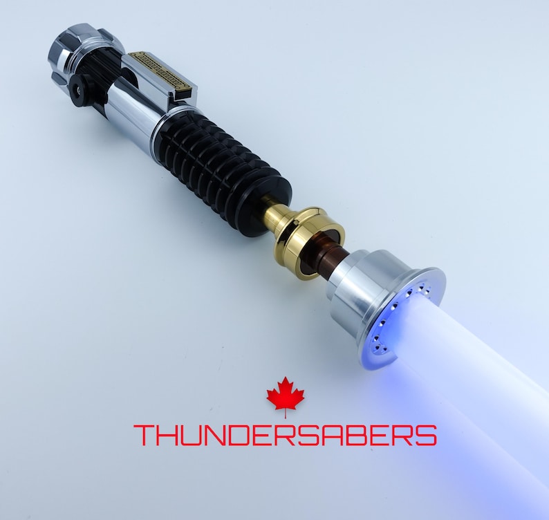 May include: A silver and black lightsaber with a blue glowing blade. The hilt features metallic accents and a ribbed grip. The text "THUNDERSABERS" is displayed below the lightsaber.