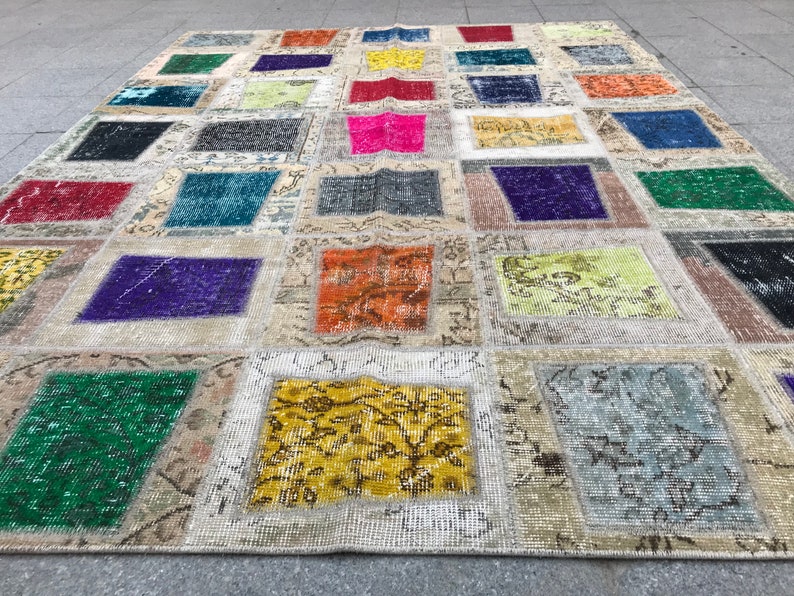 May include: A patchwork rug featuring a range of colours and patterns, including red, blue, green, yellow, and purple. The rug is crafted from various fabrics and textures, and has a distressed appearance.
