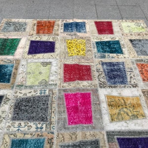May include: A patchwork rug featuring a range of colours and patterns, including red, blue, green, yellow, and pink. The rug is crafted from various fabrics and textures, and has a distressed appearance.