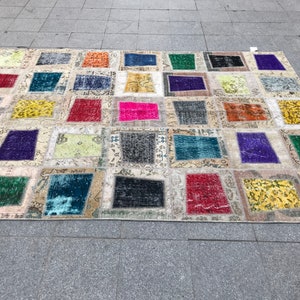 May include: A patchwork rug featuring a range of colours and patterns. The rug is composed of squares of different fabrics, each with a unique design. The rug is a great way to add a touch of colour and personality to any room.