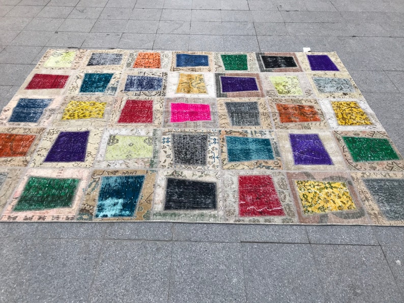 May include: A patchwork rug featuring a range of colours and patterns. The rug is composed of squares of different fabrics, each with a unique design. The rug is a great way to add a touch of colour and personality to any room.