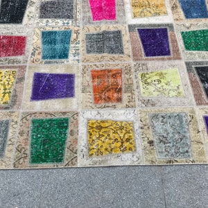 May include: A patchwork rug featuring a range of colours and patterns, including red, blue, green, yellow, and purple. The rug is crafted from various fabrics and textures, and has a distressed appearance.