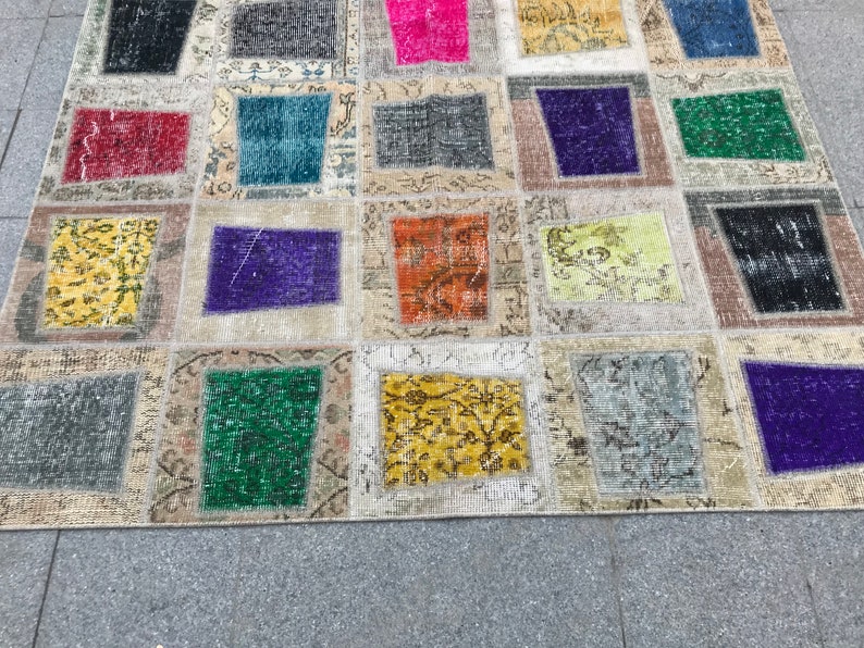 May include: A patchwork rug featuring a range of colours and patterns, including red, blue, green, yellow, and purple. The rug is crafted from various fabrics and textures, and has a distressed appearance.