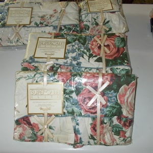 May include: Four packages of Supercale Elite flat sheets in a floral print with pink and green roses. The packages are wrapped in clear plastic with a white ribbon tied in a bow.