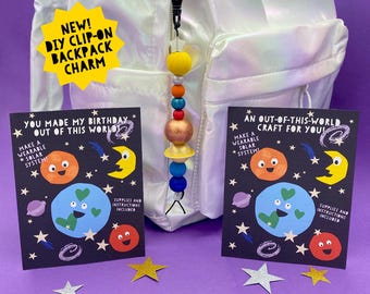 May include: A DIY clip-on backpack charm featuring a colorful planet bead design. Two cards with a wearable solar system craft are displayed, along with star-shaped confetti. The cards read "You made my birthday out of this world" and "An out-of-this-world craft for you!"