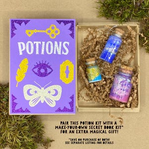 May include: A purple glittery book with the word "POTIONS" and various gold and white illustrations. Next to the book is a wooden box with three small glass bottles filled with colorful glitter and cork stoppers. The text on the image says "PAIR THIS POTION KIT WITH A MAKE-YOUR-OWN SECRET BOOK KIT* FOR AN EXTRA MAGICAL GIFT!"