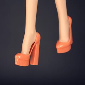 May include: A pair of coral-colored platform heels with a high heel and a closed toe.