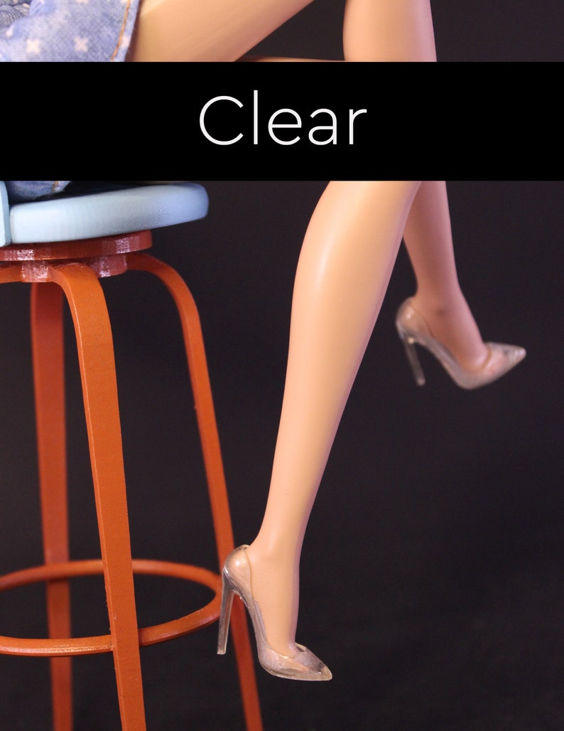Puede incluir: Un par de zapatos de tac&oacute;n alto transparentes con punta puntiaguda. Los zapatos son usados por una persona sentada en un taburete. La palabra "Claro" est&aacute; escrita en blanco sobre un fondo negro.