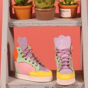 May include: A pair of colorful high-top sneakers with purple, pink, green, yellow, and orange accents. The sneakers have a white sole and a small anchor symbol on the side.