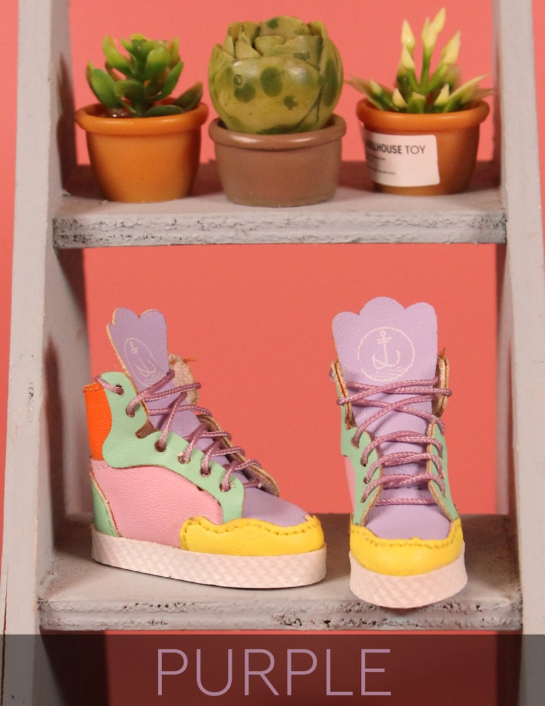 May include: A pair of colorful high-top sneakers with purple, pink, green, yellow, and orange accents. The sneakers have a white sole and a small anchor symbol on the side.