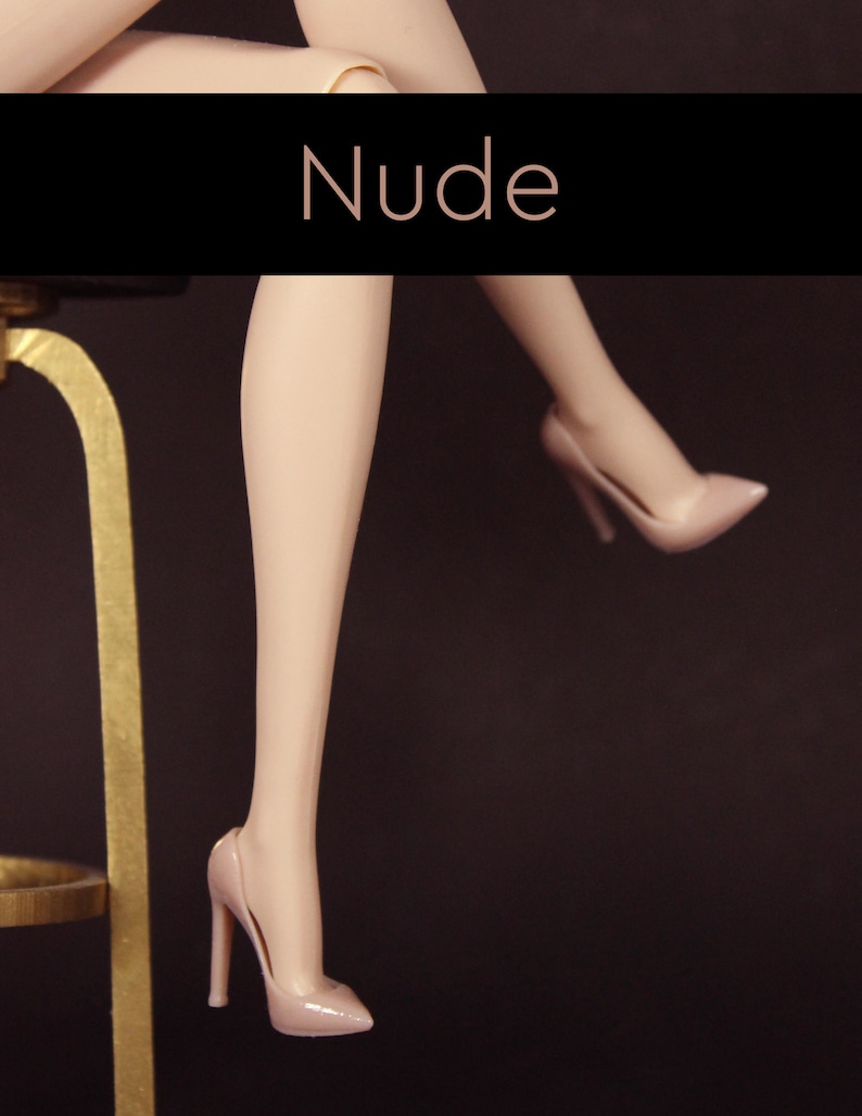 Puede incluir: Un par de tacones altos de color nude con punta. Los tacones est&aacute;n sobre un fondo oscuro.