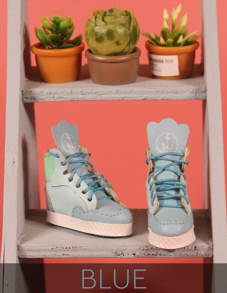 May include: A pair of blue high-top sneakers with white soles and green accents. The sneakers have an anchor logo on the side and blue laces.