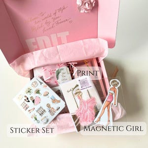May include: A pink box with a sticker set, a print of a woman in a pink dress, and a magnetic girl sticker. The box is open and the items are visible inside. The box has the text "Welcome to her world of style Styled by you Loved Forever" on the top.
