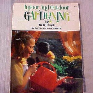 May include: A vintage book cover titled "Indoor And Outdoor Gardening for Young People" with a photo of a young person holding a red watering can. The cover has green and black text on a cream background.