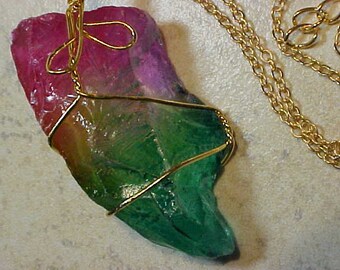 May include: A green and pink crystal pendant wrapped in gold wire, hanging from a gold chain.