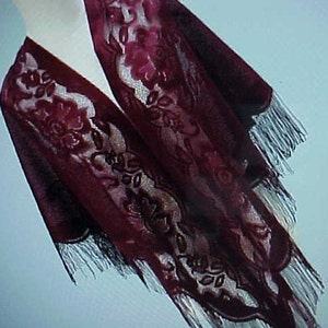 May include: A burgundy velvet shawl with a floral pattern and fringe trim.