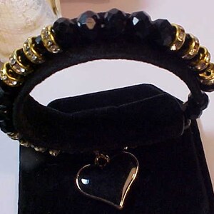 May include: Black beaded bracelet with gold accents and a black heart charm.