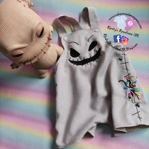 Può includere: Un body per neonato grigio con un viso di Jack Skellington cucito in nero e luci di Natale ricamate colorate sul lato. Il body ha le bretelle ed è realizzato in un tessuto morbido e confortevole.