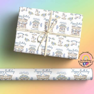 May include: Gift wrap with a carousel pattern in blue and beige, and the words "Happy Birthday." The wrapped present is tied with twine. A roll of matching wrapping paper is also visible.