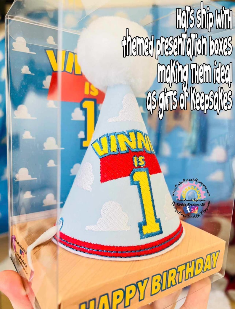 May include: A light blue birthday party hat with the name "VINNI IS 1" in yellow and red, and a white pom-pom. The hat is in a clear box with the words "HAPPY BIRTHDAY" on the box.