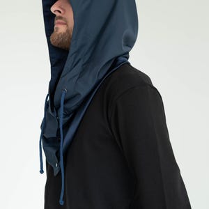 May include: A dark blue hood with a smooth, matte finish and a matching drawstring. The hood features a structured design that covers the head and neck, with metal eyelets for the drawstring and a button closure at the front neck area.