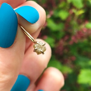 May include: A delicate gold ring with a small, raw, light brown diamond. The diamond is set in a simple, four-prong setting.