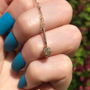 May include: A delicate gold chain necklace with a small, square-shaped, rough-cut diamond pendant.