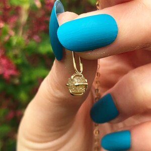 May include: A gold necklace with a small, rough, yellow gemstone pendant. The pendant is shaped like a small, irregular cube.
