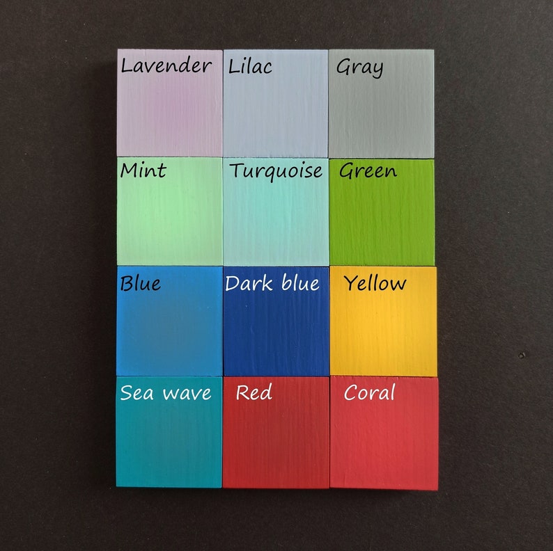 May include: A color chart with 12 painted wooden squares. The squares are arranged in a 3x4 grid. The colors are lavender, lilac, gray, mint, turquoise, green, blue, dark blue, yellow, sea wave, red, and coral.