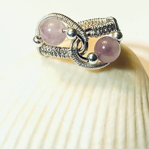 Op de afbeelding: Een zilveren ring met draad gewikkeld met twee lichtpaarse edelsteen kralen.
