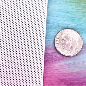 May include: A close-up of a white sheet with a grid of small black dots. The sheet is next to a strand of colorful hair and a US dime coin. The text .5MM is visible in the top right corner of the image.