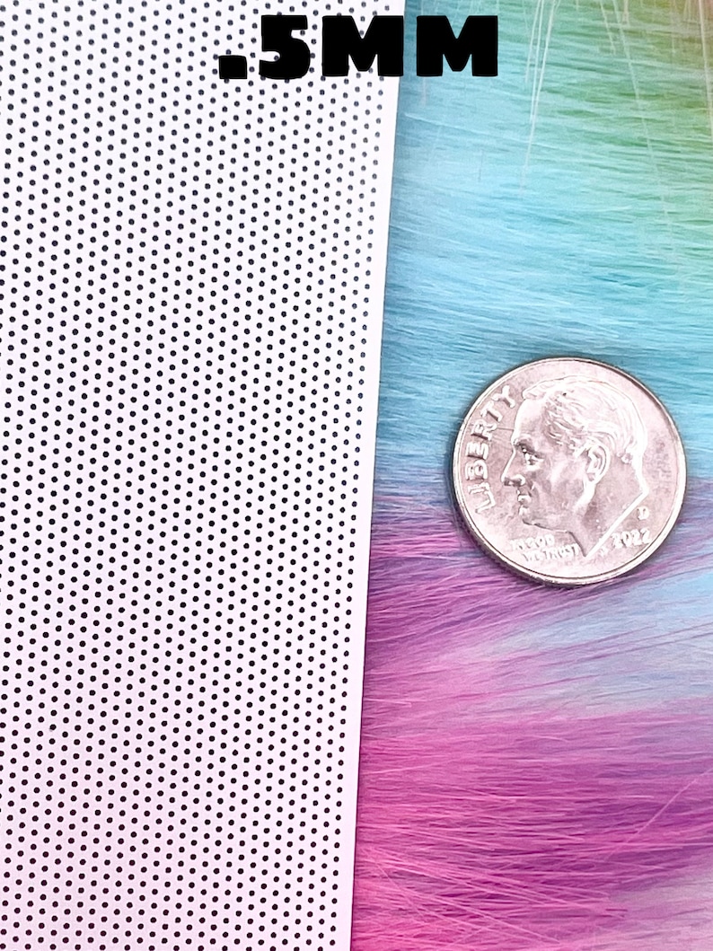 May include: A close-up of a white sheet with a grid of small black dots. The sheet is next to a strand of colorful hair and a US dime coin. The text .5MM is visible in the top right corner of the image.