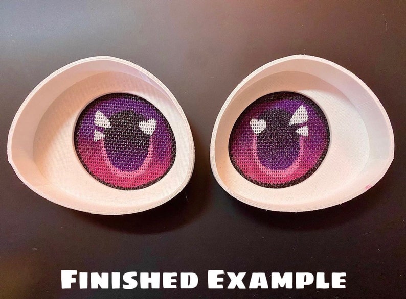 May include: Two white, curved eye sockets with a purple and pink eye design. The eyes have a mesh-like texture with white heart-shaped highlights. The text "FINISHED EXAMPLE" is at the bottom.