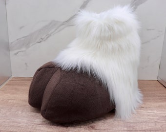 May include: A brown plush foot with white fur on top. The foot is shaped like a human foot and has a rounded toe.