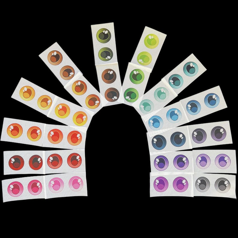 May include: Assortment of colorful plastic eyes, arranged in a rainbow pattern on a white background. The eyes are various sizes and have black pupils.