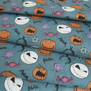 May include: Fabric with a teal background featuring a repeating pattern of orange jack-o'-lanterns, white Jack Skellington faces, bats, purple lollipops, and pink candies. The fabric is folded, showing multiple layers.