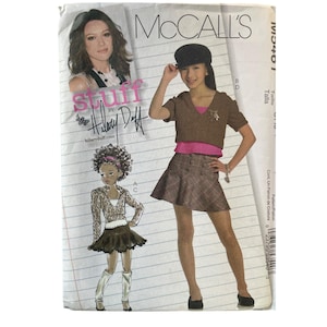 May include: McCall's sewing pattern featuring a design by Hilary Duff. The pattern includes illustrations of clothing designs, with the text "stuff by Hilary Duff" and "hilaryduff.com" visible. The pattern is labeled with the McCall's logo.