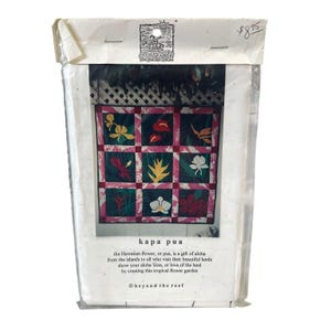 May include: A packaged craft kit featuring a colorful floral quilt design. The quilt pattern includes nine squares with various tropical flower illustrations in shades of pink, green, and white. Text on the package reads "kapa pua" and describes the Hawaiian flower.